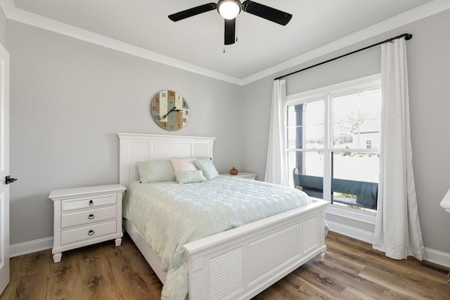 bedroom with hardwood / wood-style flooring, ceiling fan, and crown molding