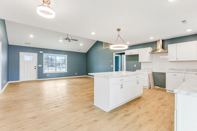 kitchen with light hardwood / wood-style flooring, white cabinets, wall chimney exhaust hood, and pendant lighting