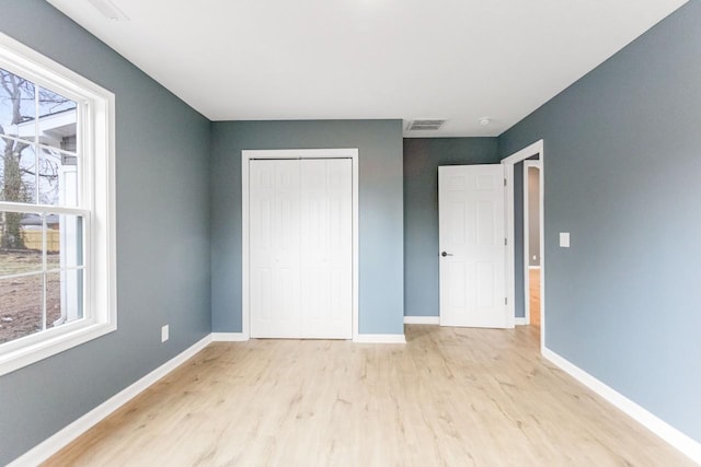 unfurnished bedroom featuring light wood-type flooring and a closet