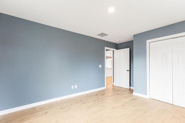 unfurnished bedroom with light hardwood / wood-style flooring and a closet