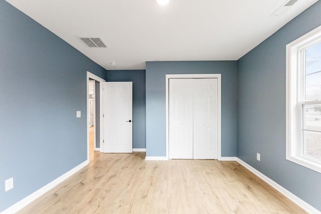 unfurnished bedroom featuring light hardwood / wood-style floors and a closet