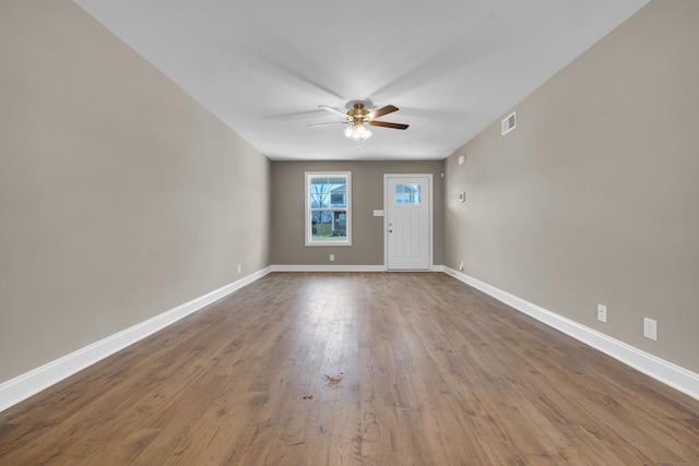 interior space featuring visible vents, wood finished floors, a ceiling fan, and baseboards