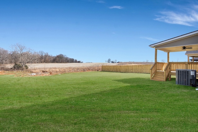 view of yard featuring fence, a ceiling fan, and cooling unit