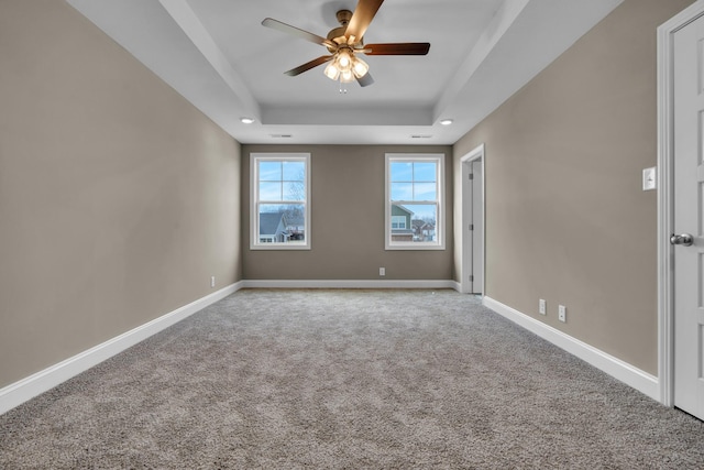 unfurnished room with a ceiling fan, a tray ceiling, carpet flooring, and baseboards