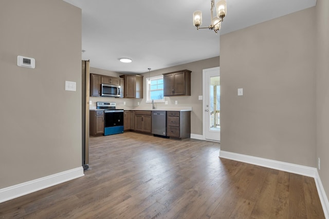 kitchen with baseboards, appliances with stainless steel finishes, light countertops, and wood finished floors