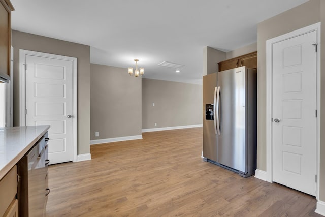 kitchen with light wood-style floors, baseboards, light countertops, and stainless steel fridge with ice dispenser