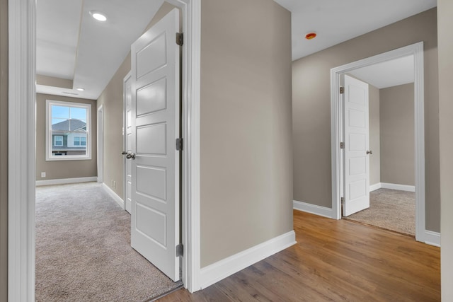 corridor with carpet flooring, baseboards, and wood finished floors