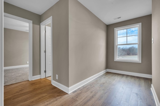 empty room with visible vents, baseboards, and wood finished floors