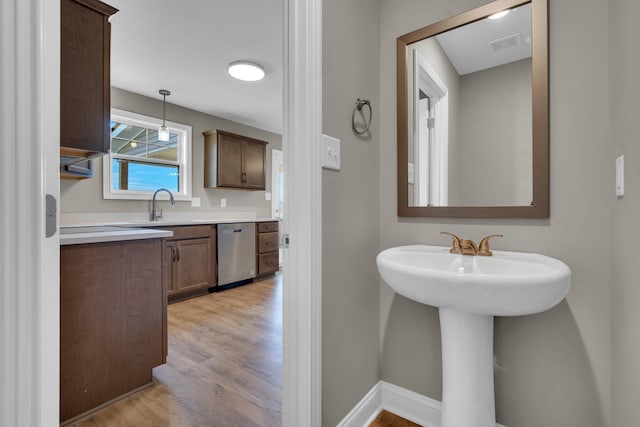 bathroom featuring visible vents, a sink, baseboards, and wood finished floors