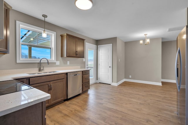 kitchen featuring pendant lighting, stainless steel appliances, a sink, and light wood-style floors