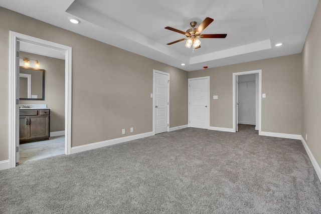 unfurnished bedroom with carpet, a tray ceiling, baseboards, and recessed lighting