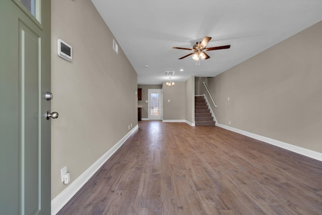 unfurnished living room featuring ceiling fan, wood finished floors, visible vents, baseboards, and stairs