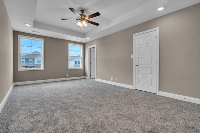 empty room with baseboards, a ceiling fan, a tray ceiling, carpet floors, and recessed lighting