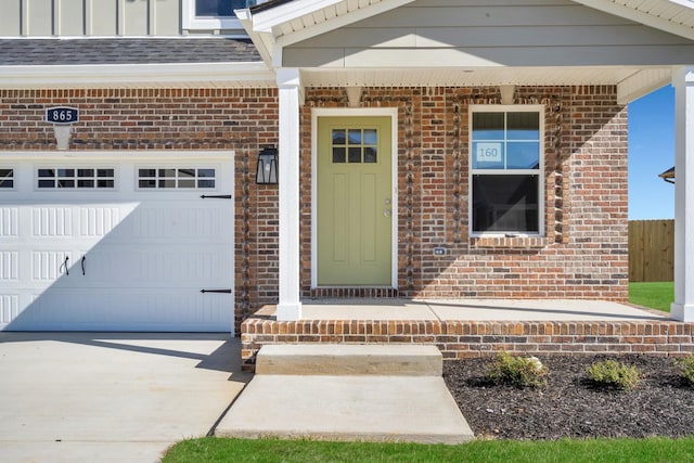 entrance to property with board and batten siding, brick siding, driveway, and roof with shingles