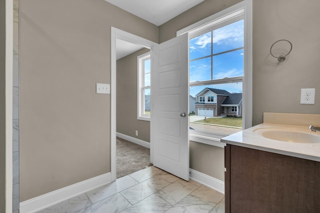 bathroom featuring marble finish floor, plenty of natural light, baseboards, and vanity