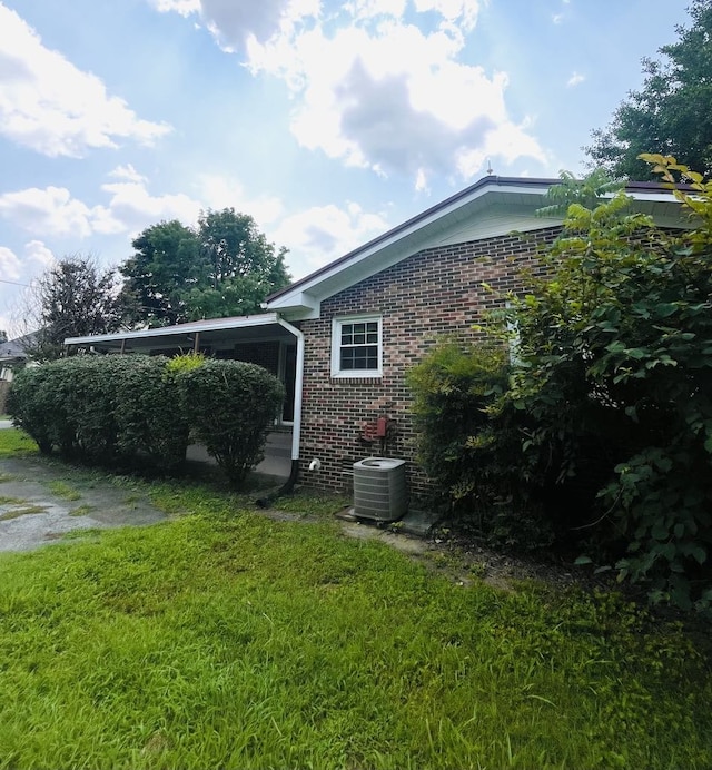 view of side of home featuring central air condition unit and a yard