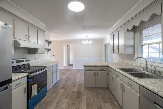 kitchen with stainless steel appliances, sink, light hardwood / wood-style floors, crown molding, and a chandelier