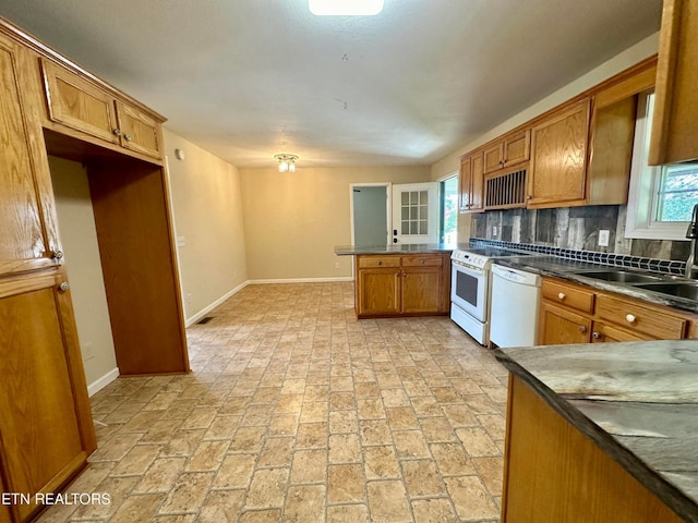 kitchen featuring white appliances, kitchen peninsula, sink, and tasteful backsplash