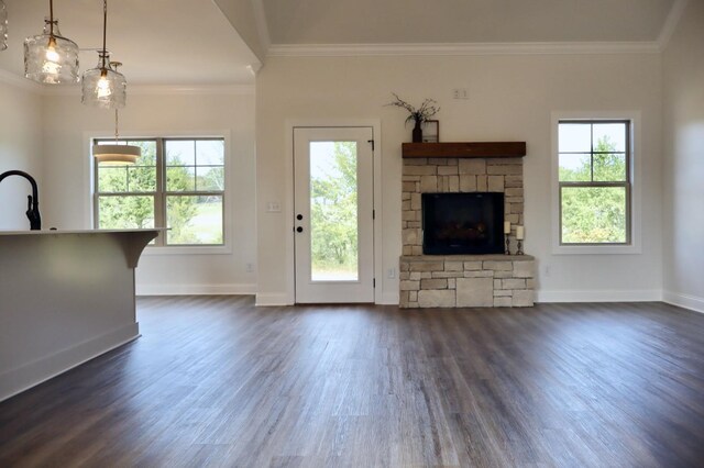 unfurnished living room with crown molding, a stone fireplace, and dark hardwood / wood-style floors