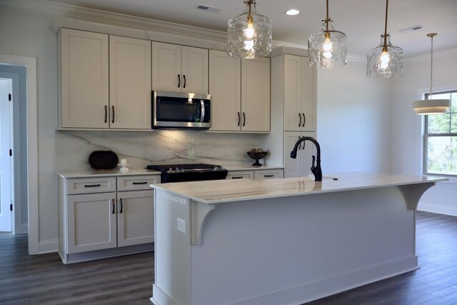 kitchen featuring an island with sink, a breakfast bar area, and hanging light fixtures