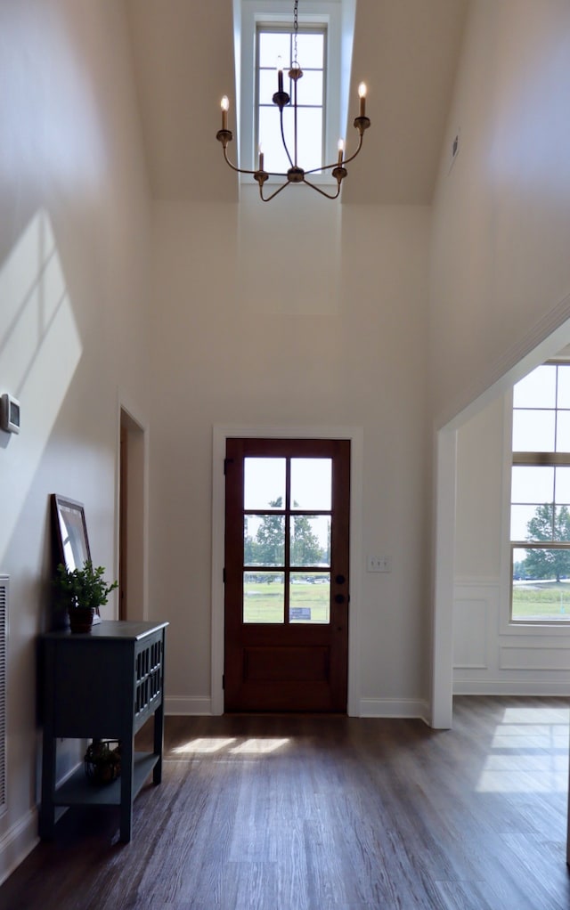 foyer featuring high vaulted ceiling, a wealth of natural light, a chandelier, and dark hardwood / wood-style floors