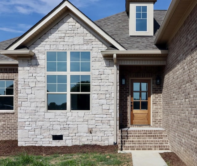 property entrance with a shingled roof, crawl space, and stone siding