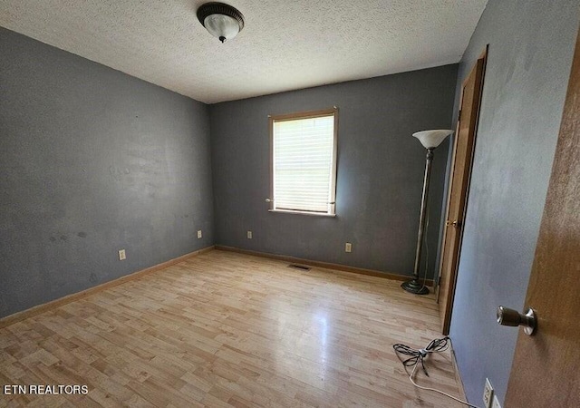 unfurnished room with wood finished floors, visible vents, and baseboards