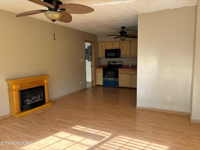 kitchen featuring light wood-style flooring, a fireplace, black microwave, and electric range oven