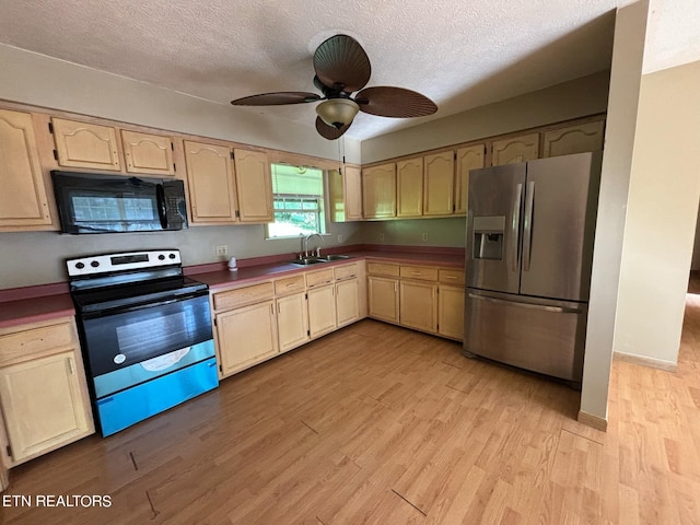 kitchen featuring light wood finished floors, ceiling fan, appliances with stainless steel finishes, a textured ceiling, and a sink