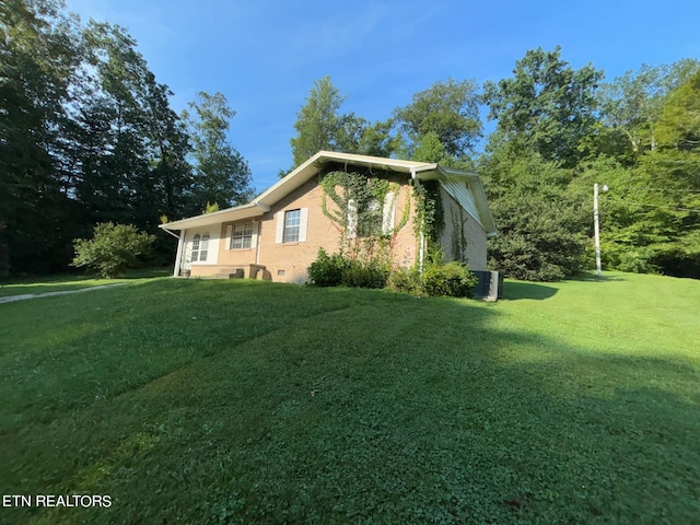 view of side of property featuring crawl space, a lawn, and brick siding