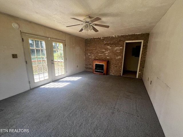 unfurnished living room featuring a ceiling fan, a textured ceiling, french doors, carpet floors, and a fireplace