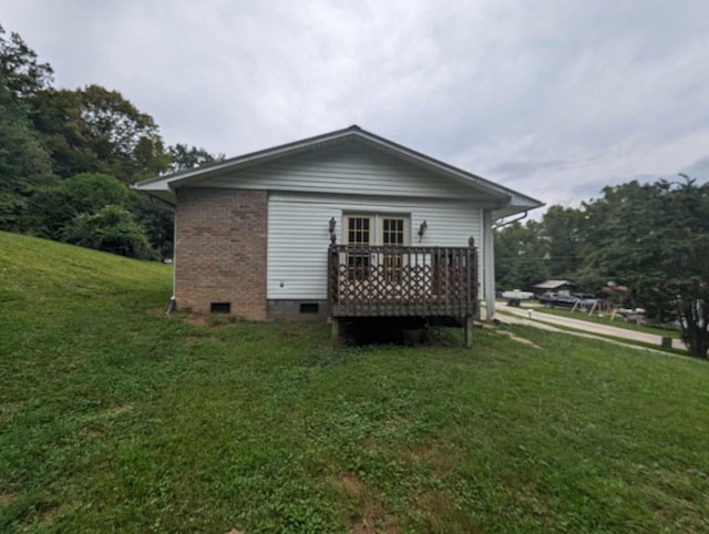 rear view of house with crawl space, a lawn, brick siding, and a deck