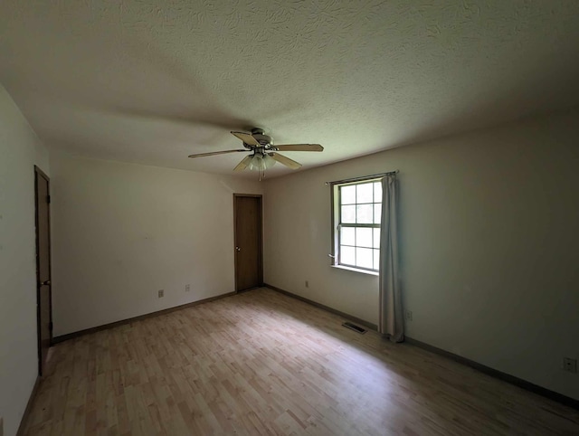 unfurnished room with visible vents, baseboards, ceiling fan, light wood-style flooring, and a textured ceiling