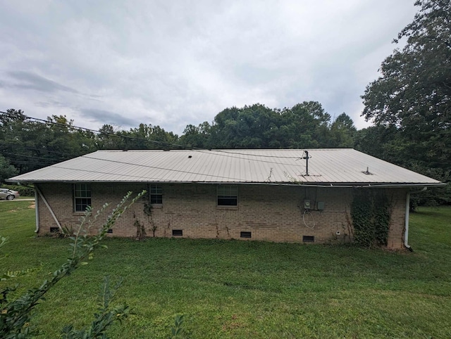 rear view of house featuring crawl space, a yard, metal roof, and brick siding