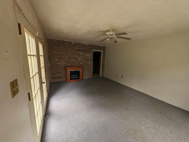 unfurnished living room with a ceiling fan, a brick fireplace, carpet, and a textured ceiling