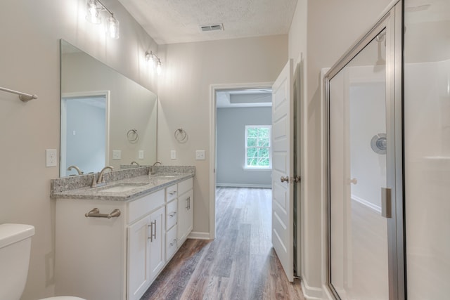 bathroom featuring walk in shower, toilet, a textured ceiling, vanity, and hardwood / wood-style floors