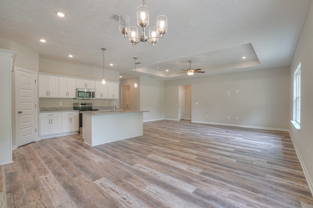 kitchen featuring white cabinetry, stainless steel appliances, a tray ceiling, and hanging light fixtures