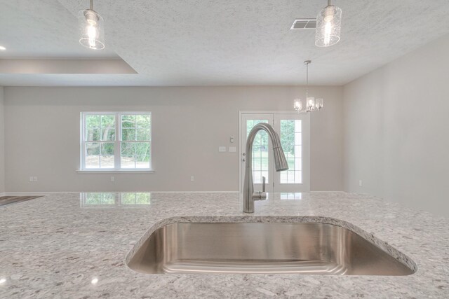 kitchen featuring sink, hanging light fixtures, and a textured ceiling