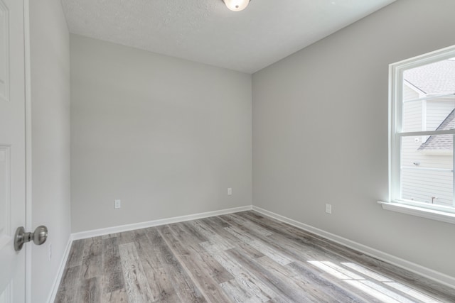 unfurnished room with a textured ceiling and light hardwood / wood-style flooring