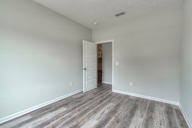 spare room featuring wood-type flooring and a textured ceiling