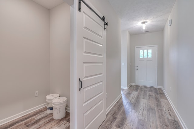 doorway to outside featuring wood-type flooring, a barn door, and a textured ceiling