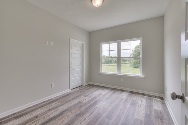 spare room with light hardwood / wood-style flooring and a textured ceiling