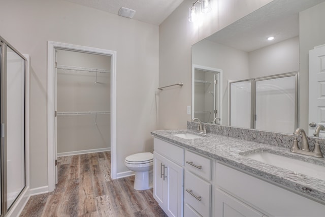 bathroom featuring hardwood / wood-style flooring, vanity, a textured ceiling, toilet, and walk in shower