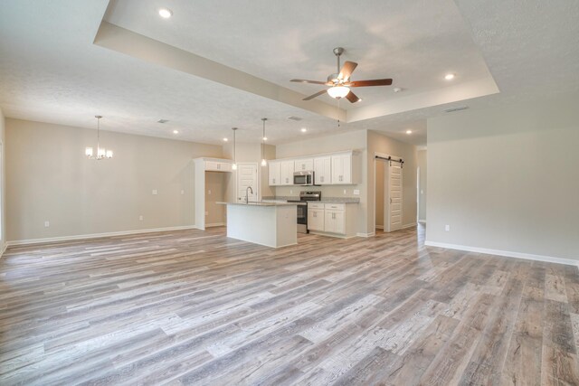 kitchen with stainless steel appliances, a center island, white cabinets, decorative light fixtures, and a barn door