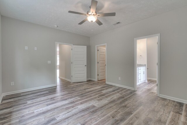 unfurnished bedroom featuring ceiling fan, light hardwood / wood-style floors, and a textured ceiling