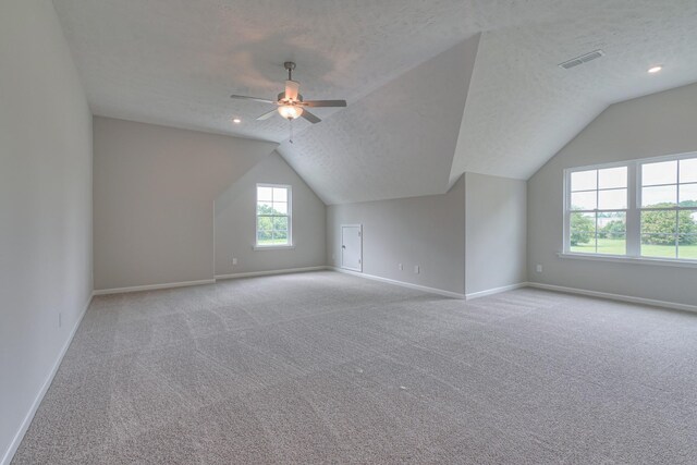 bonus room featuring light carpet, ceiling fan, vaulted ceiling, and a textured ceiling