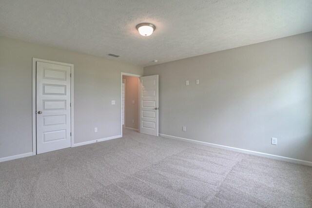 unfurnished bedroom with light colored carpet and a textured ceiling