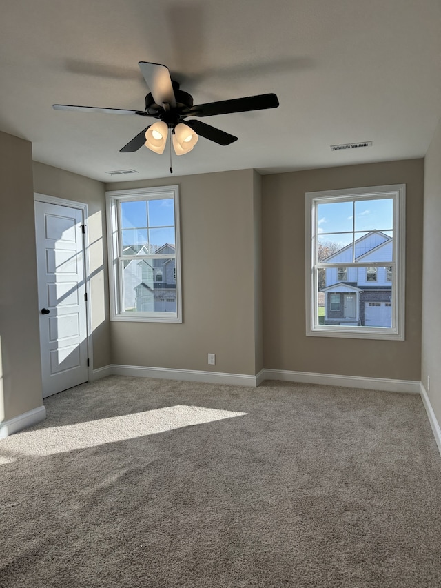 empty room with ceiling fan, light colored carpet, and a healthy amount of sunlight