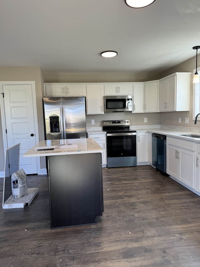 kitchen with sink, stainless steel appliances, white cabinets, dark hardwood / wood-style flooring, and decorative light fixtures