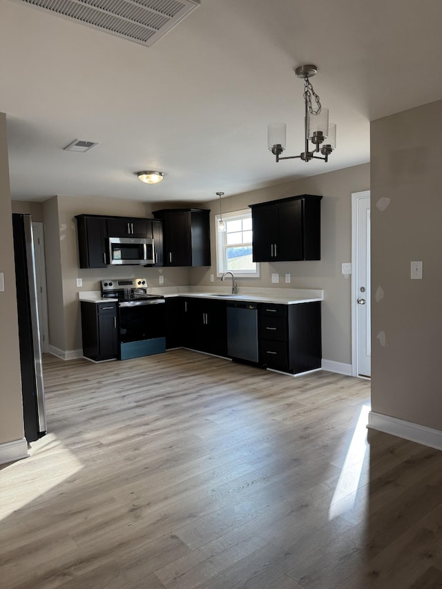 kitchen featuring sink, hanging light fixtures, stainless steel appliances, and light wood-type flooring